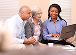Edlerly couple looking at a computer with another woman